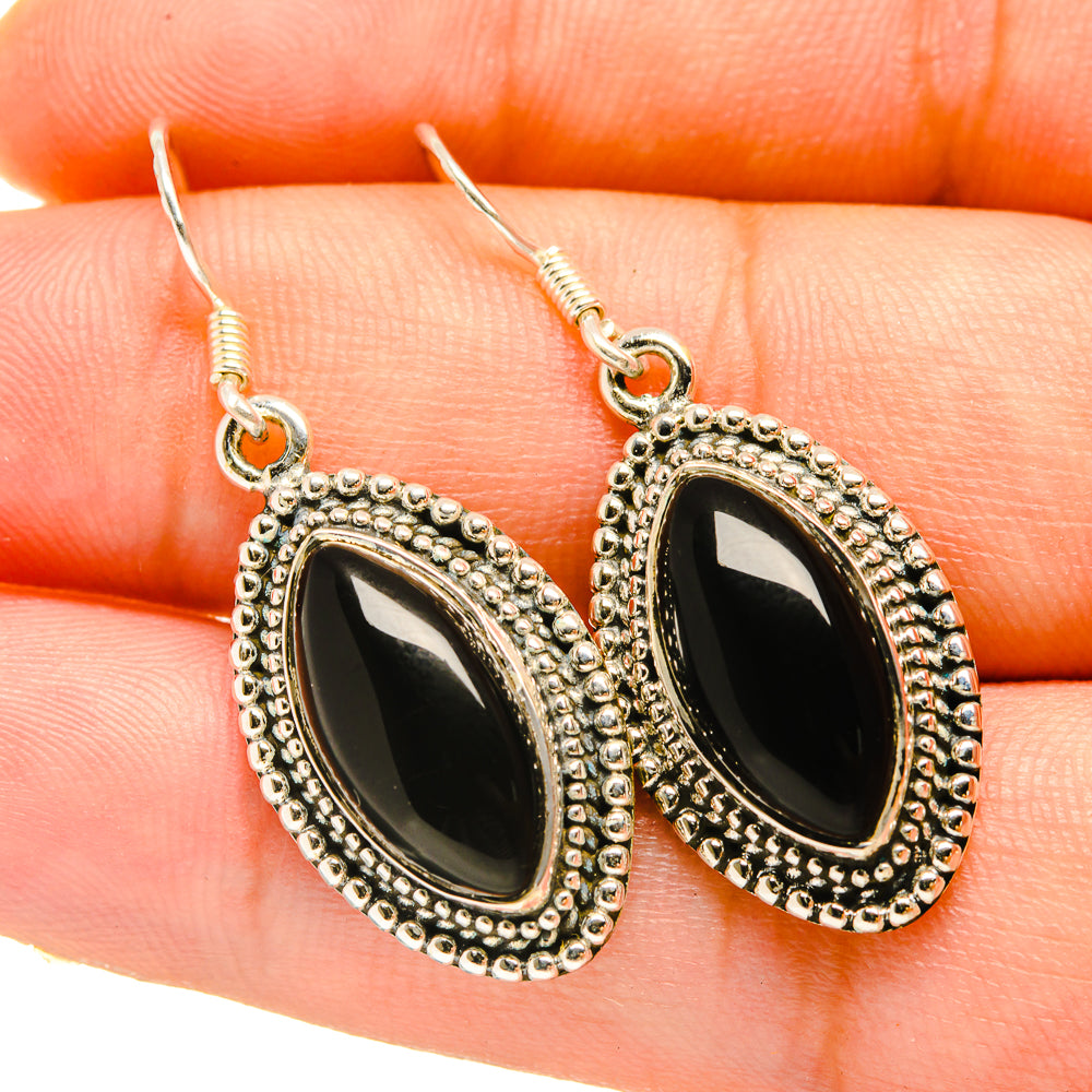 Oval black stone drop earrings with silver-tone scalloped frame on hook
