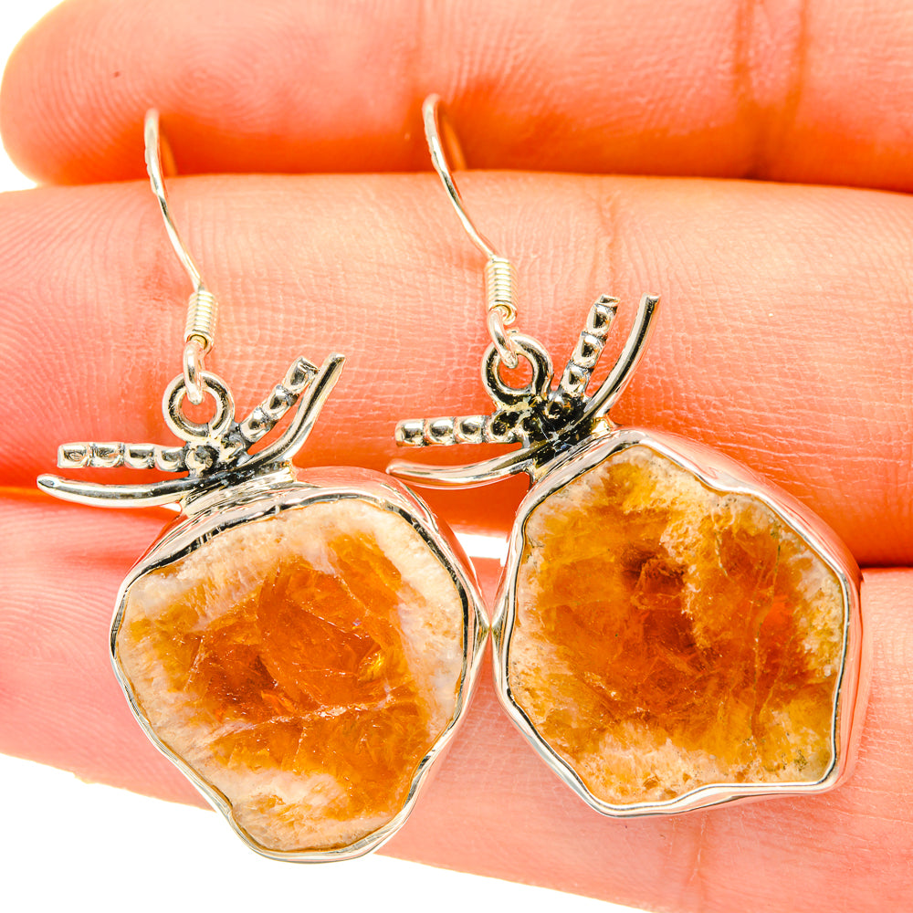 Rough citrine earrings close-up, faceted orange-yellow stones on silver leaf settings