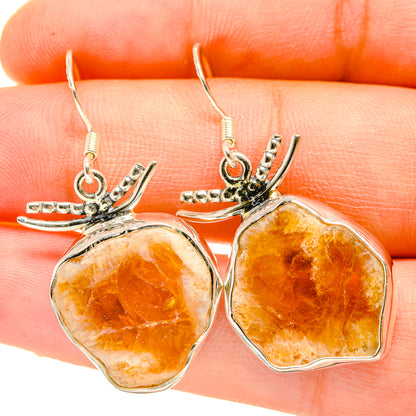 Rough citrine earrings close-up, faceted orange-yellow stones on silver leaf settings