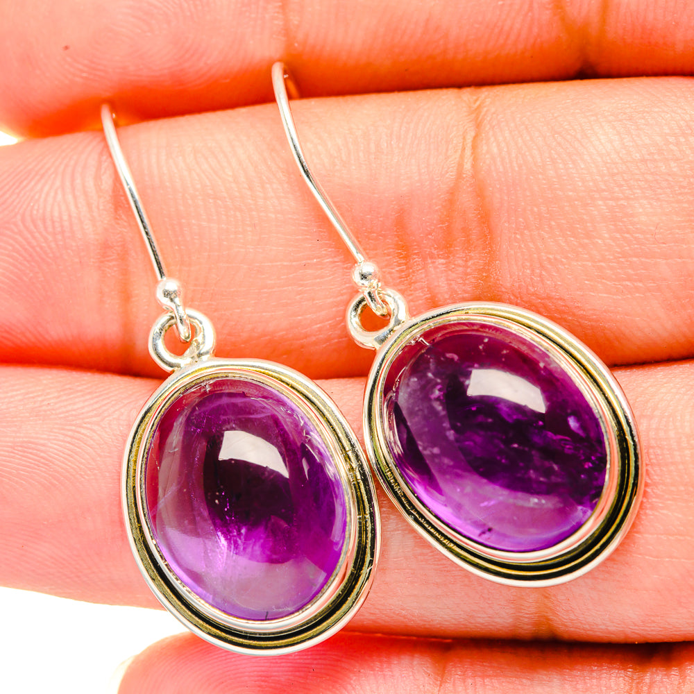 Silver earrings with oval amethyst cabochons in gold-tone halos, curved drop hooks
