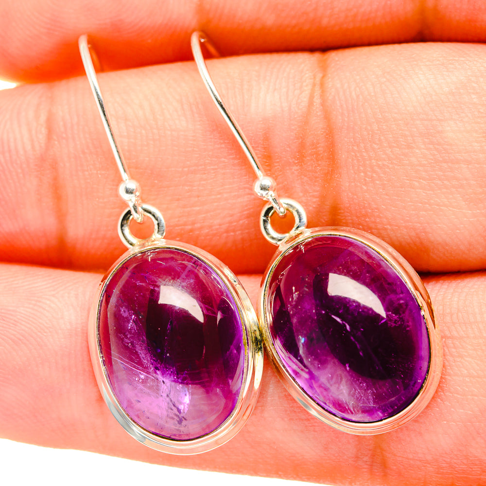 Oval amethyst drop earrings with glossy purple cabochon and silver hook clasps