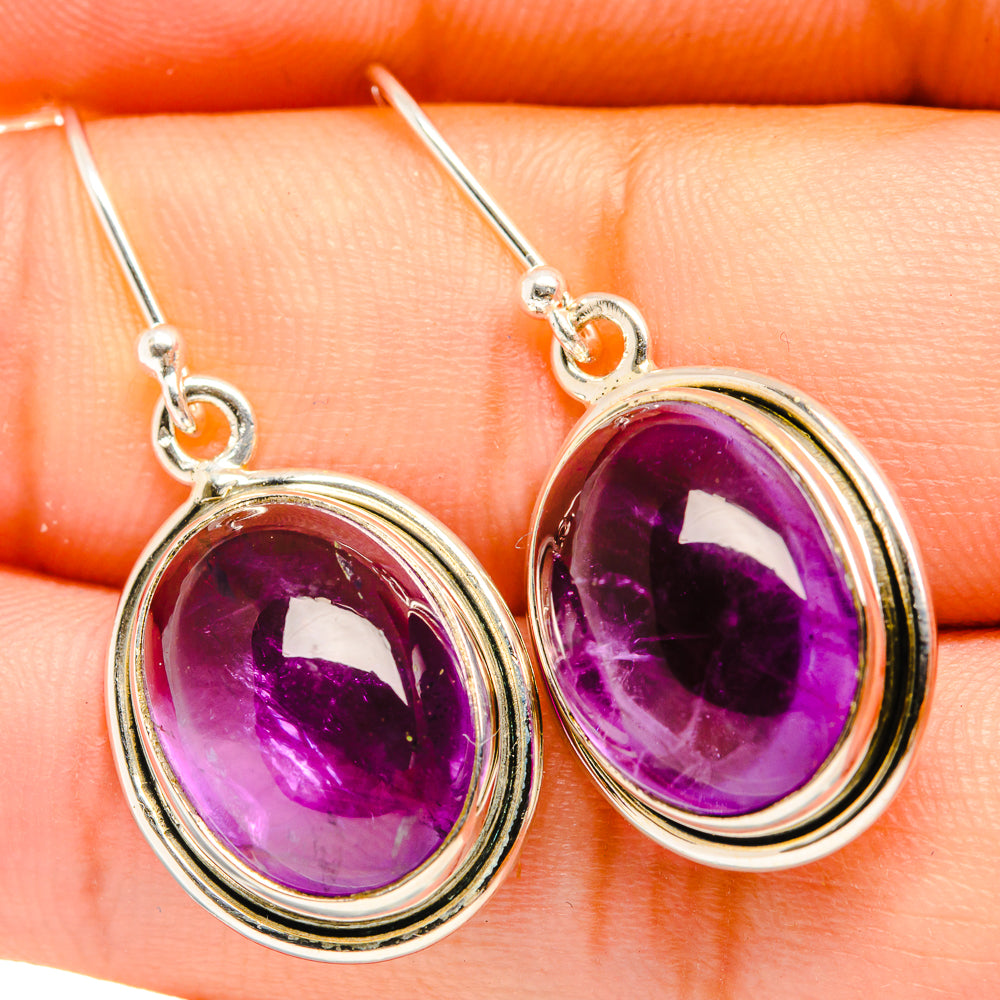 Close-up of oval purple amethyst drop earrings with sterling silver hooks and bezels