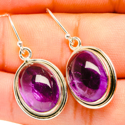 Close-up of oval purple amethyst drop earrings with sterling silver hooks and bezels