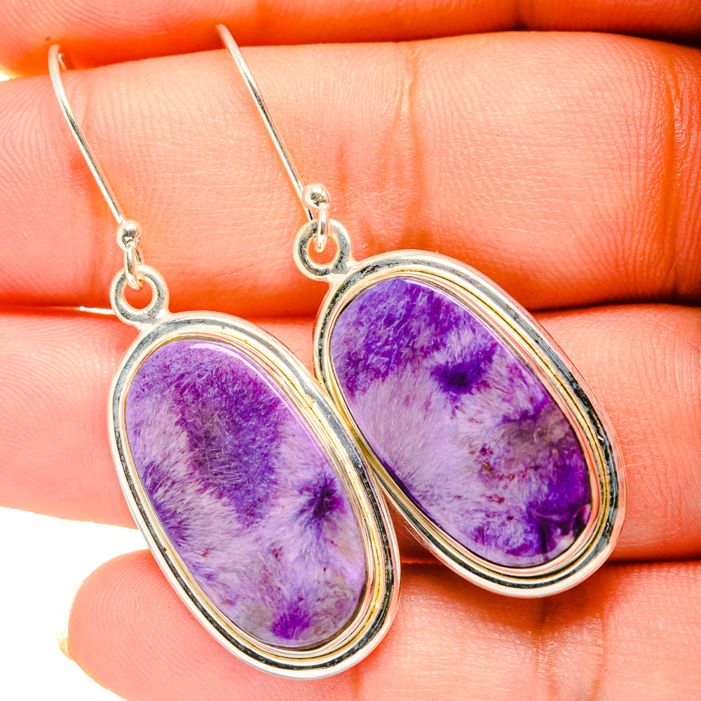 Charoite earrings close-up: oval purple cabochon in silver bezels with drop hooks
