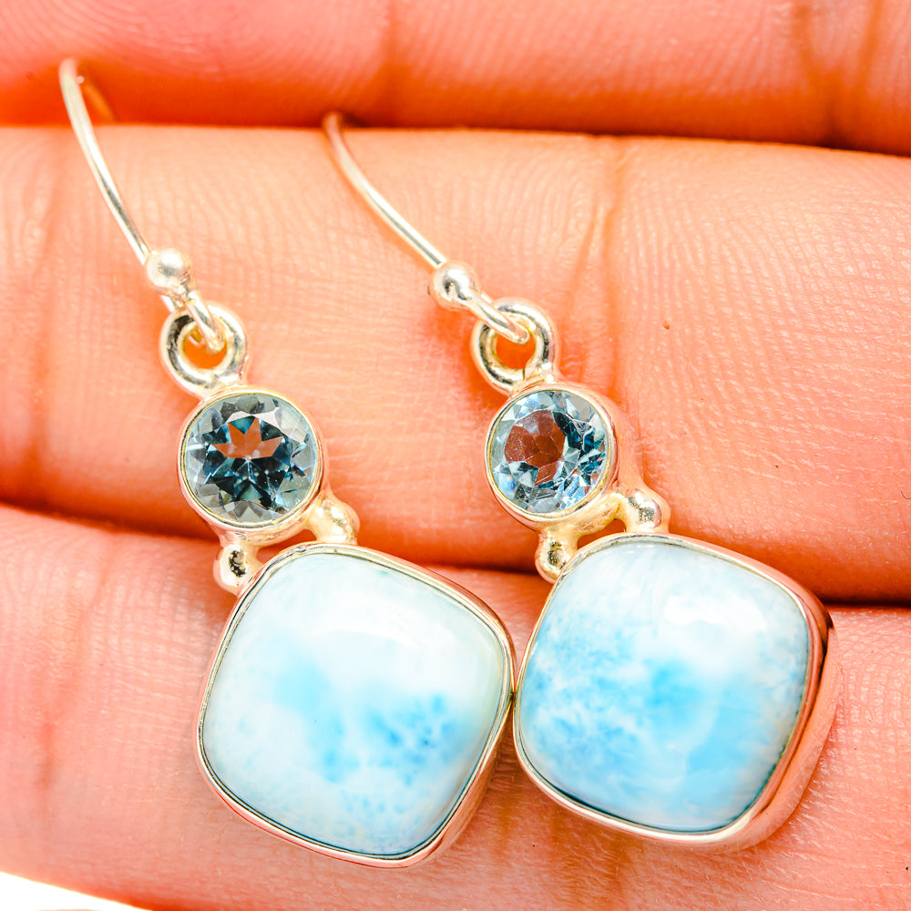 Close-up of blue gemstone drop earrings with oval larimar cabochons and round topaz settings