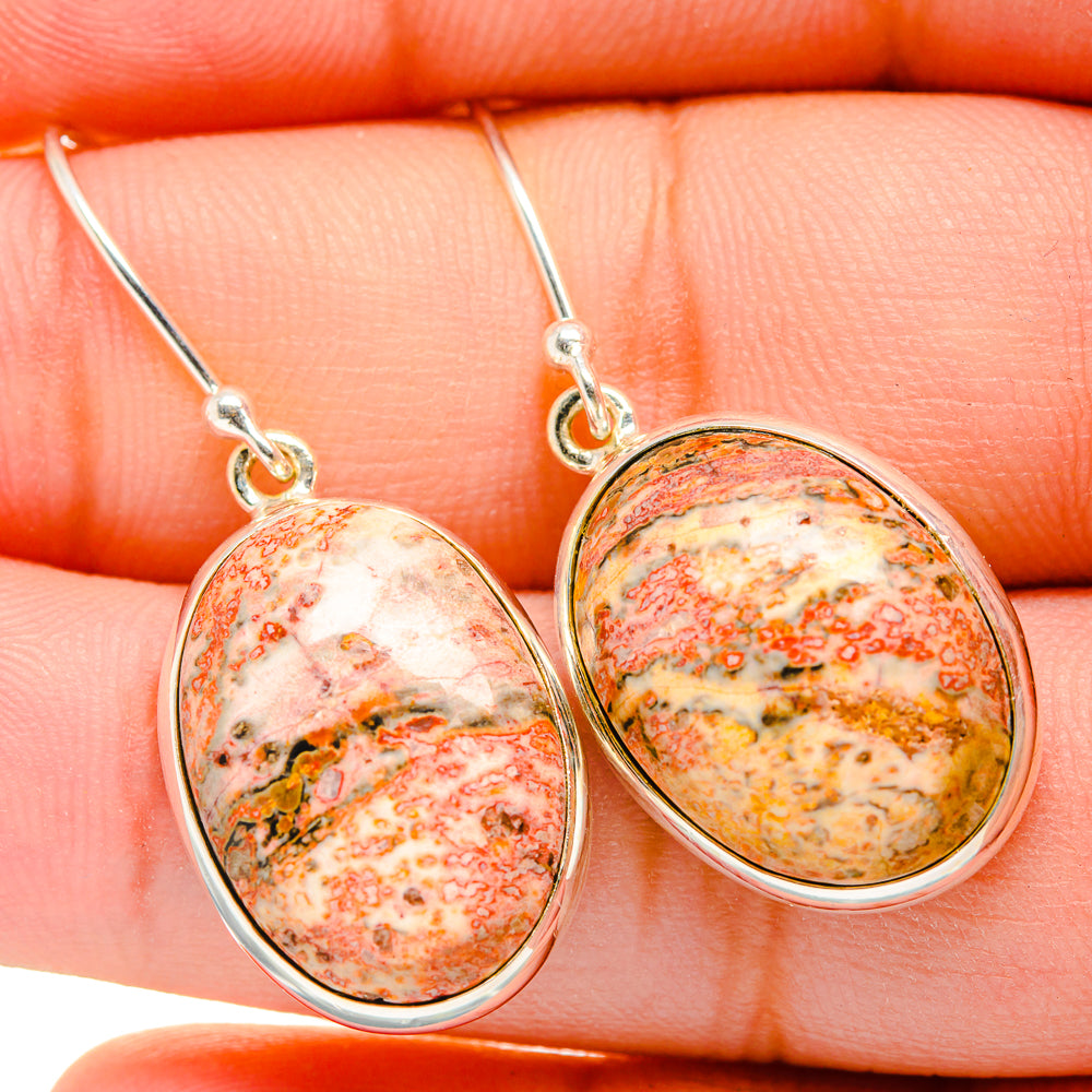 Close-up oval poppy jasper earrings with silver hooks, speckled orange, yellow, red