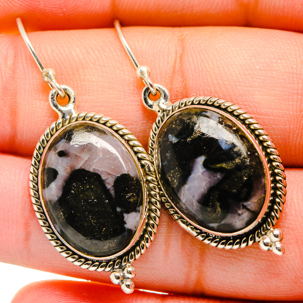 Closeup oval gabbro stone drop earrings with textured silver bezel and dangling hooks