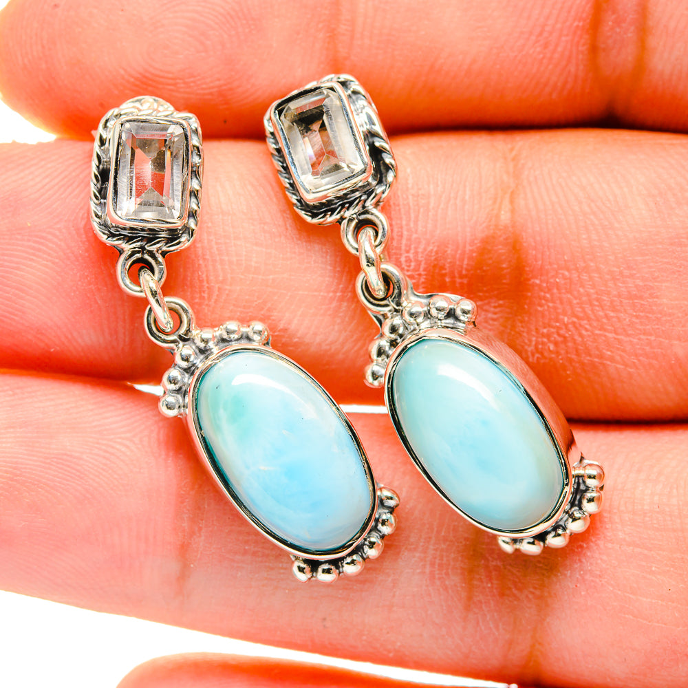 Sterling silver earrings with blue oval gemstones and small chain links, close-up