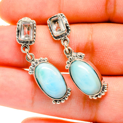 Sterling silver earrings with blue oval gemstones and small chain links, close-up