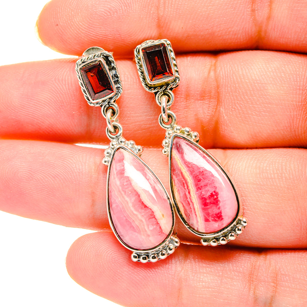 Close-up sterling silver earrings with square garnet tops and pink-red teardrop drops