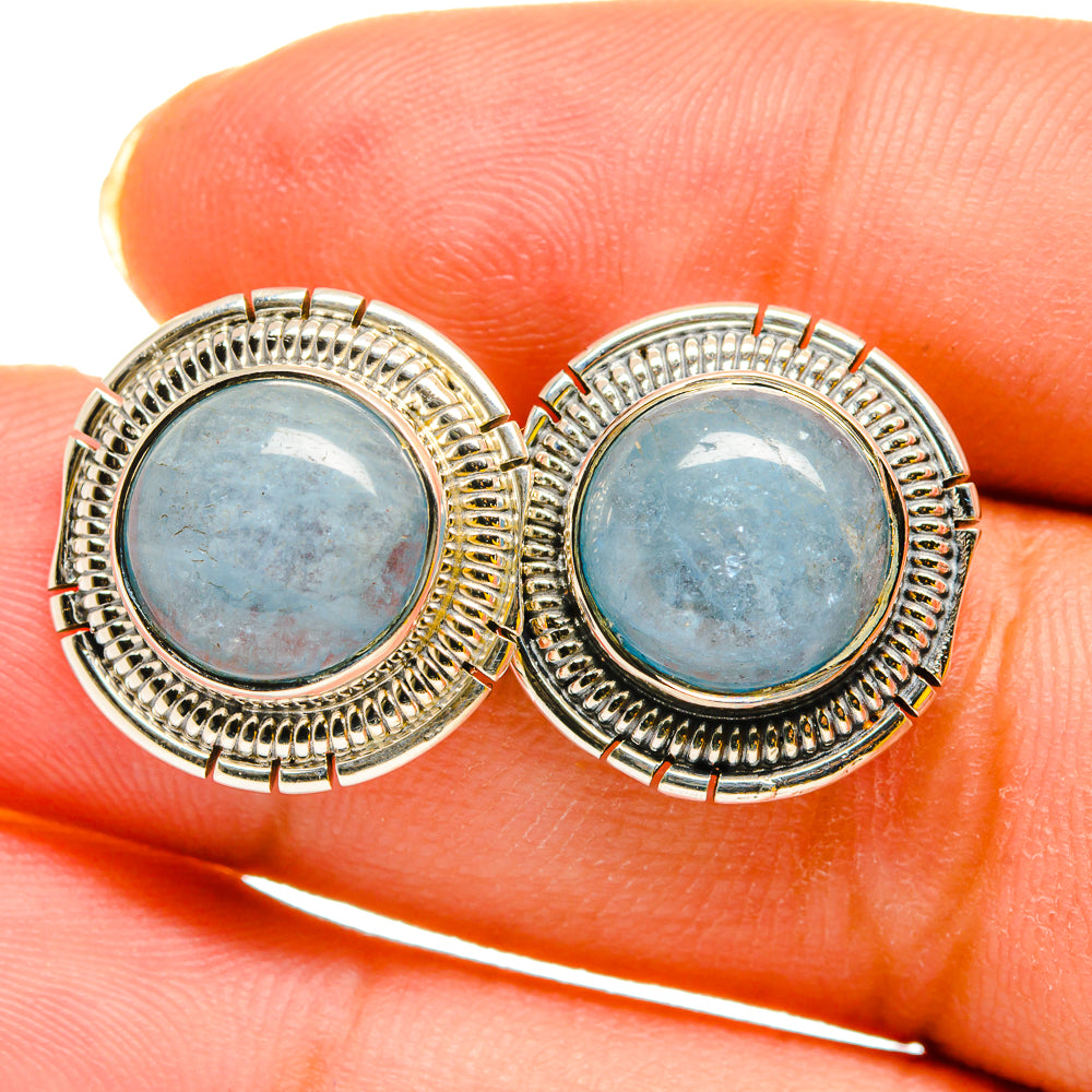 Close-up aquamarine stud earrings with round blue cabochon gemstones and silver bezel