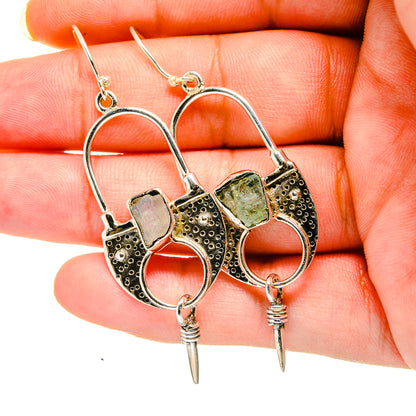 Gold-tone hoop earrings with rough aquamarine-colored stones, textured bezels, and spikes