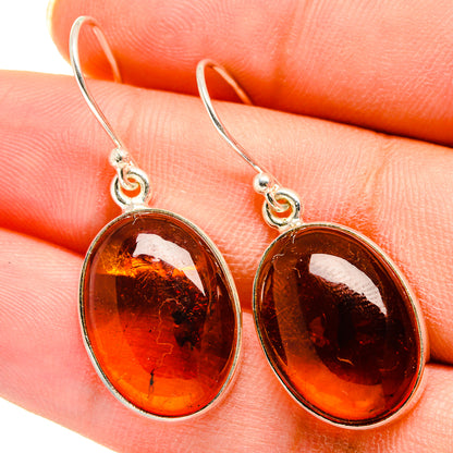 Deep orange oval amber earrings with sterling silver hooks in bezel settings