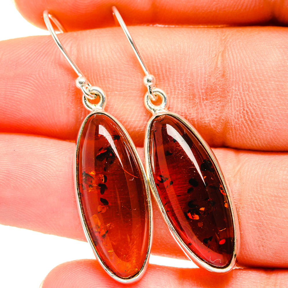 Amber drop earrings with oval dark red-orange stones, silver hook backs