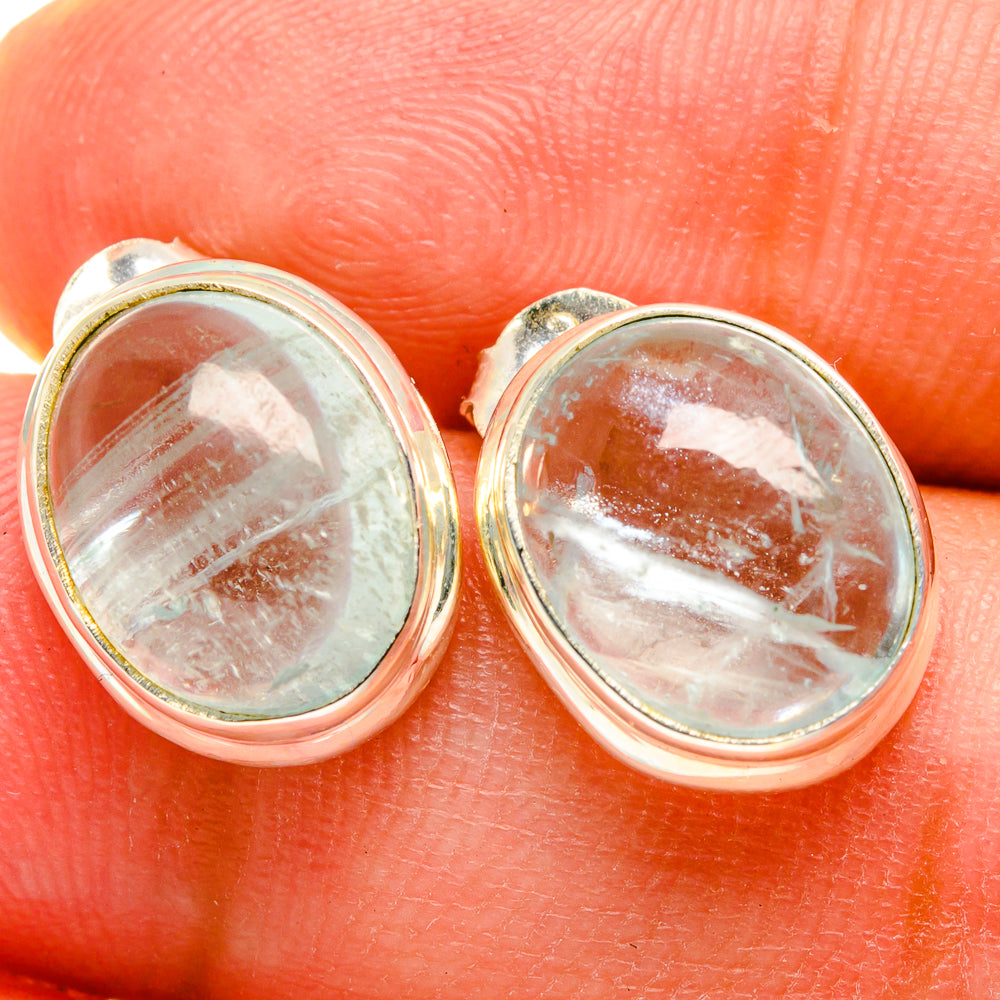 Close-up of oval aquamarine stud earrings, speckled light-blue stone in silver bezel