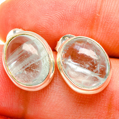 Close-up of oval aquamarine stud earrings, speckled light-blue stone in silver bezel