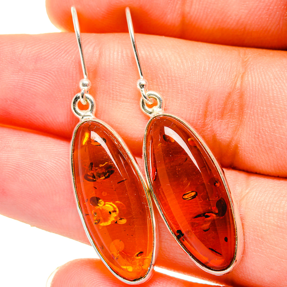 Amber oval dangle earrings with sterling silver hooks and teardrop stone settings