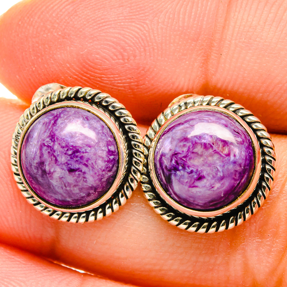 Close-up of round purple gemstone stud earrings in silver rope bezel