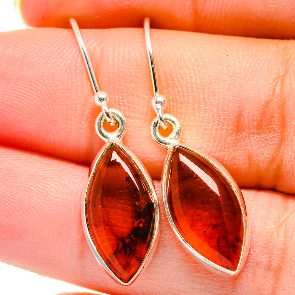 Amber teardrop dangle earrings in sterling silver with warm orange faceted, translucent centers.