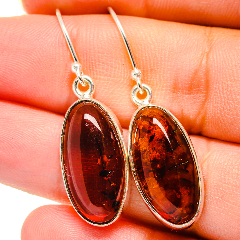 Oval amber dangle earrings with dark orange-red cabochons in silver bezels