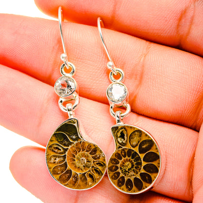 Close-up ammonite fossil earrings with white quartz top stones and sterling silver hooks