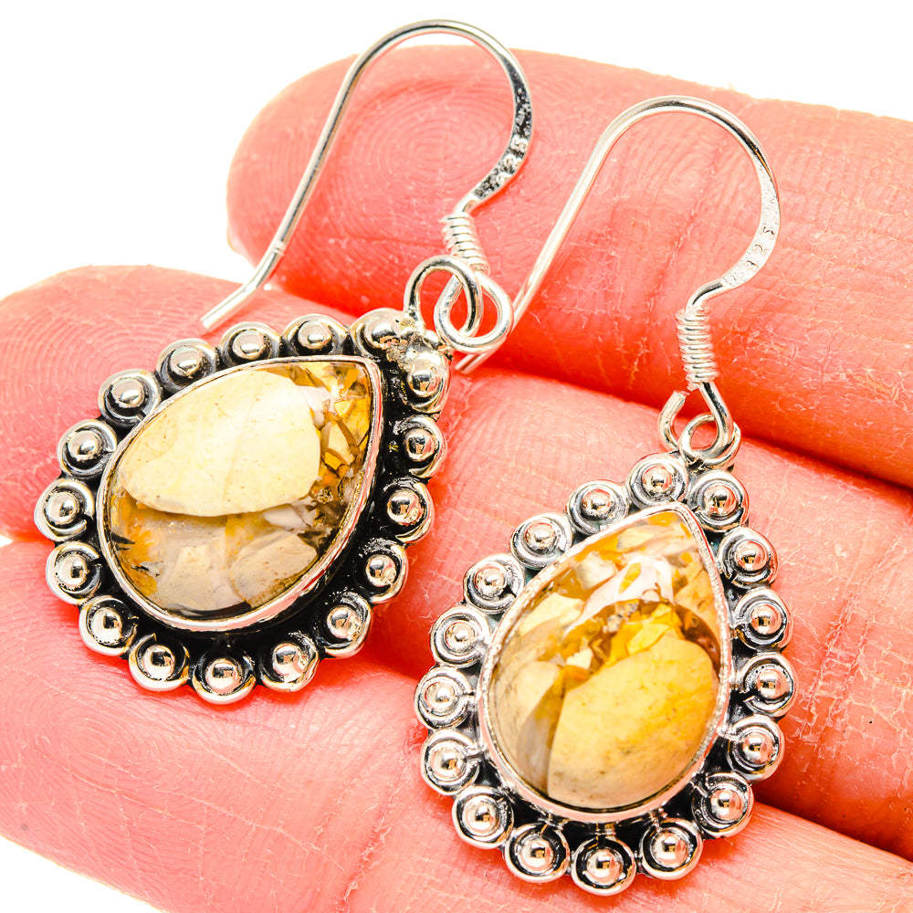 Close-up of mookaite drop earrings, teardrop yellow-orange stones in beaded silver halo hooks.