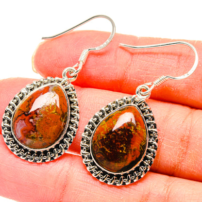 Close-up of sterling silver teardrop agate earrings with red and dark amber marbling