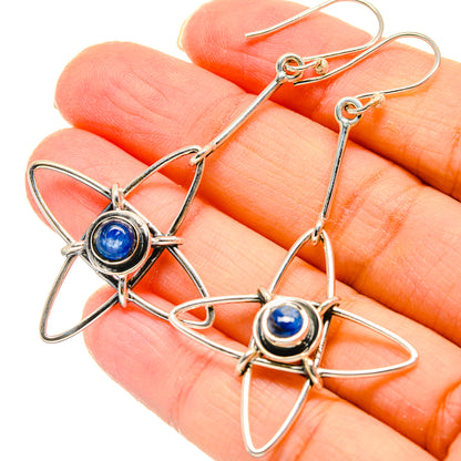 Sterling silver earrings featuring blue cabochon center and star wire loops, held up