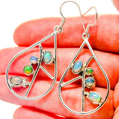 Sterling silver oval opal drop earrings with dangling multicolor stones, close-up
