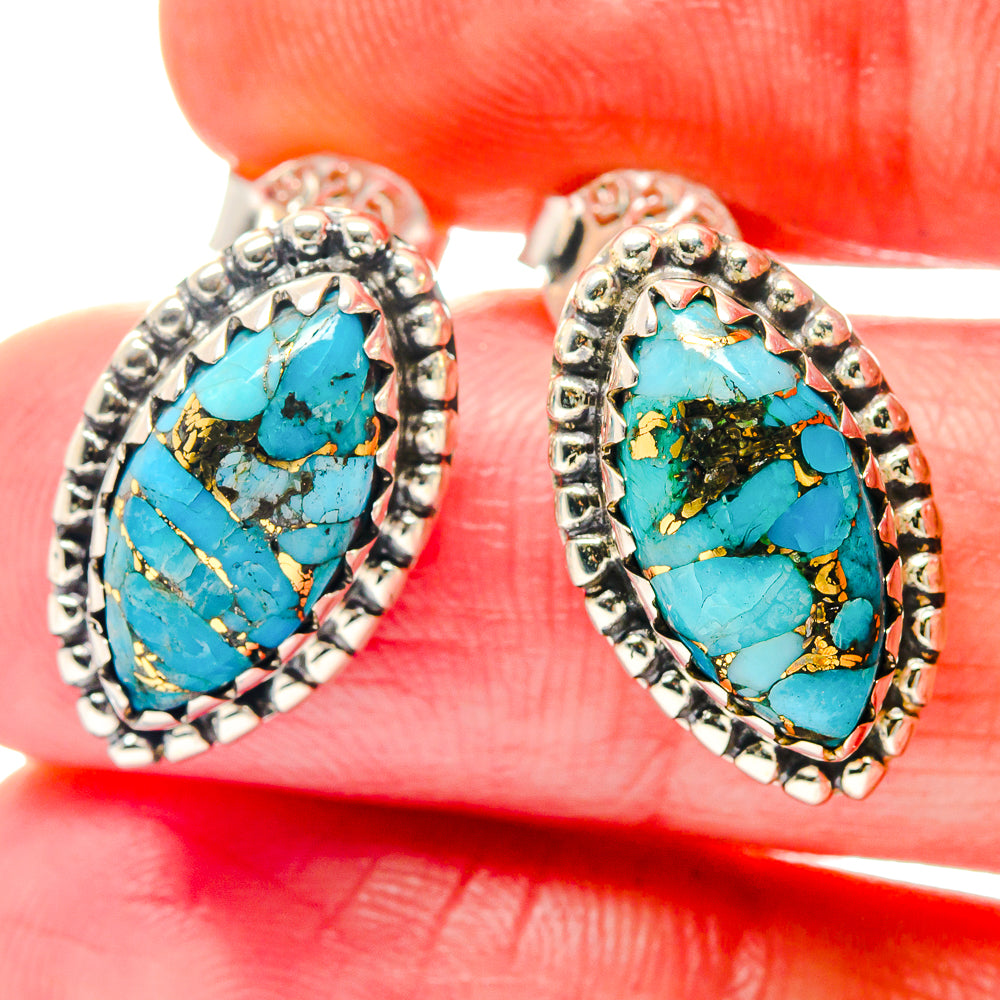 Close-up of turquoise oval gemstone earrings with gold veining in silver-tone settings