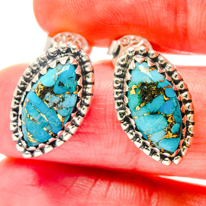 Close-up of turquoise oval gemstone earrings with gold veining in silver-tone settings