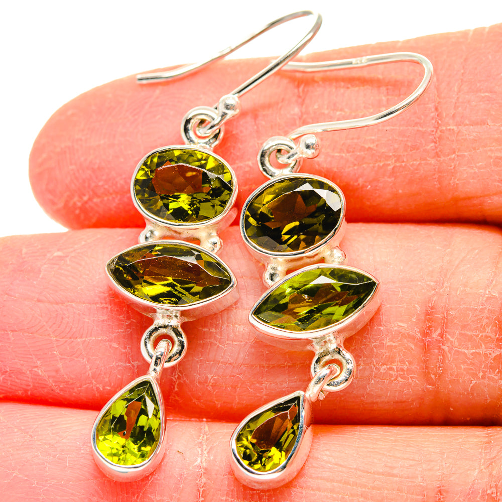 Close-up of sterling silver peridot earrings with oval green stones and fishhook