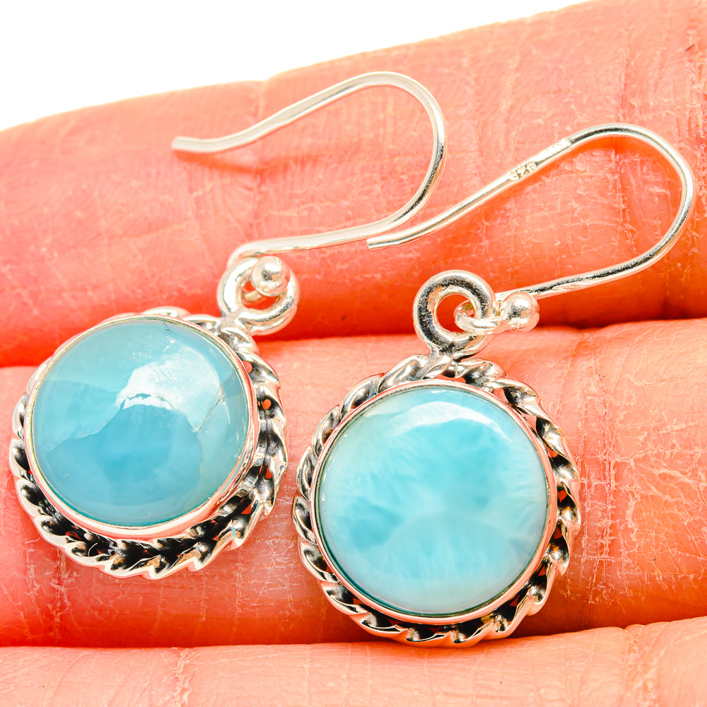 Larimar earrings close-up: round turquoise Larimar cabochon in ornate silver frame with hooks