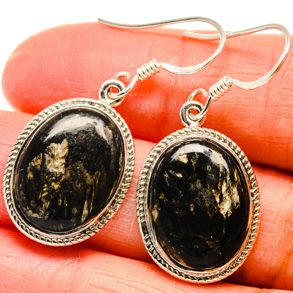Close-up oval black-green gemstone drop earrings with ornate silver bezel and hooks
