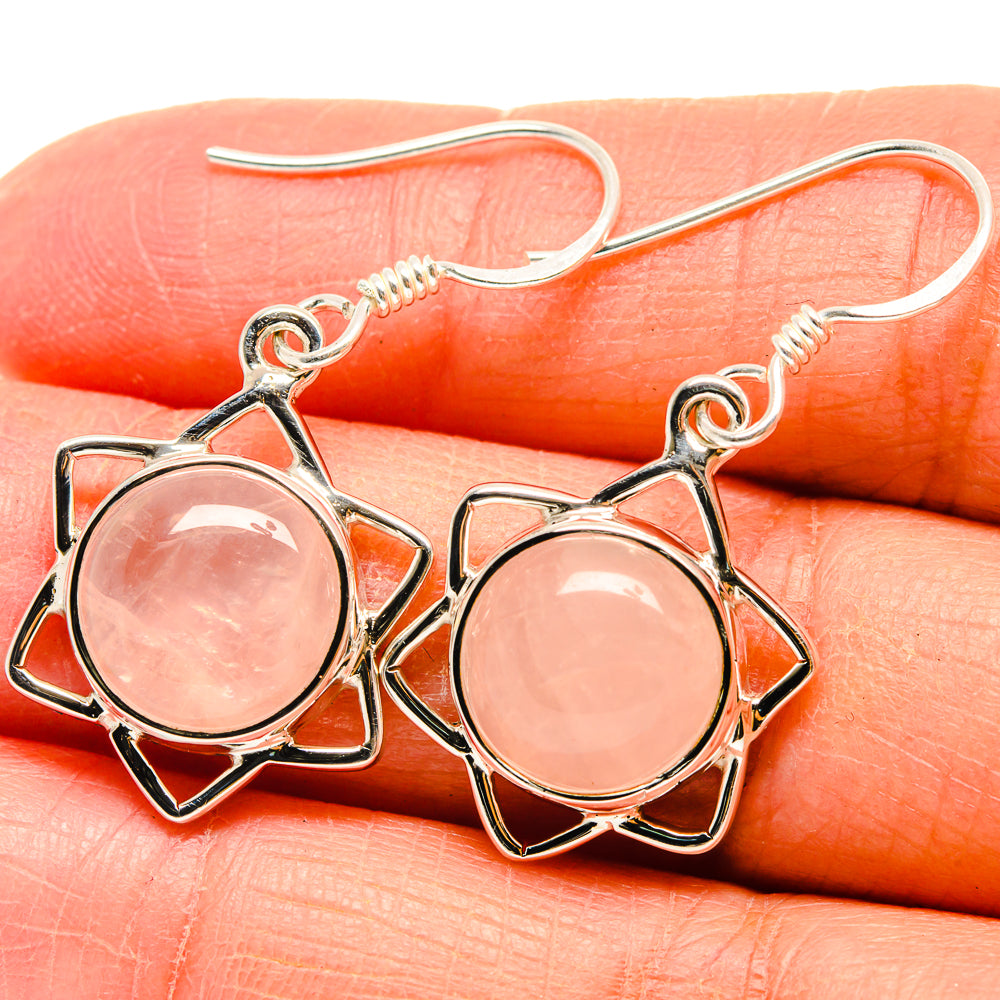 Rose quartz earrings close-up: round pink cabochon in silver star setting, hook backs