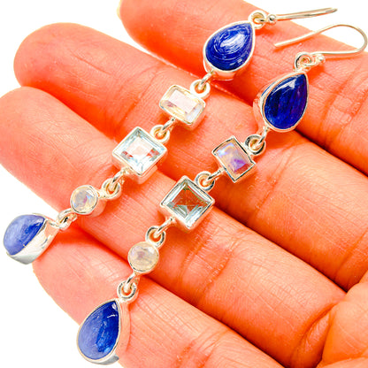 Blue teardrop and clear square dangle earrings with metal hooks, close-up.