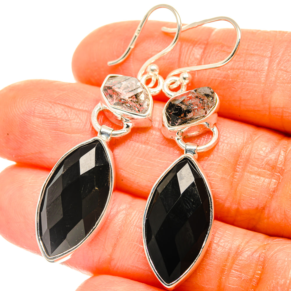 Close-up sterling silver earrings with faceted black onyx teardrops and clear rough stones
