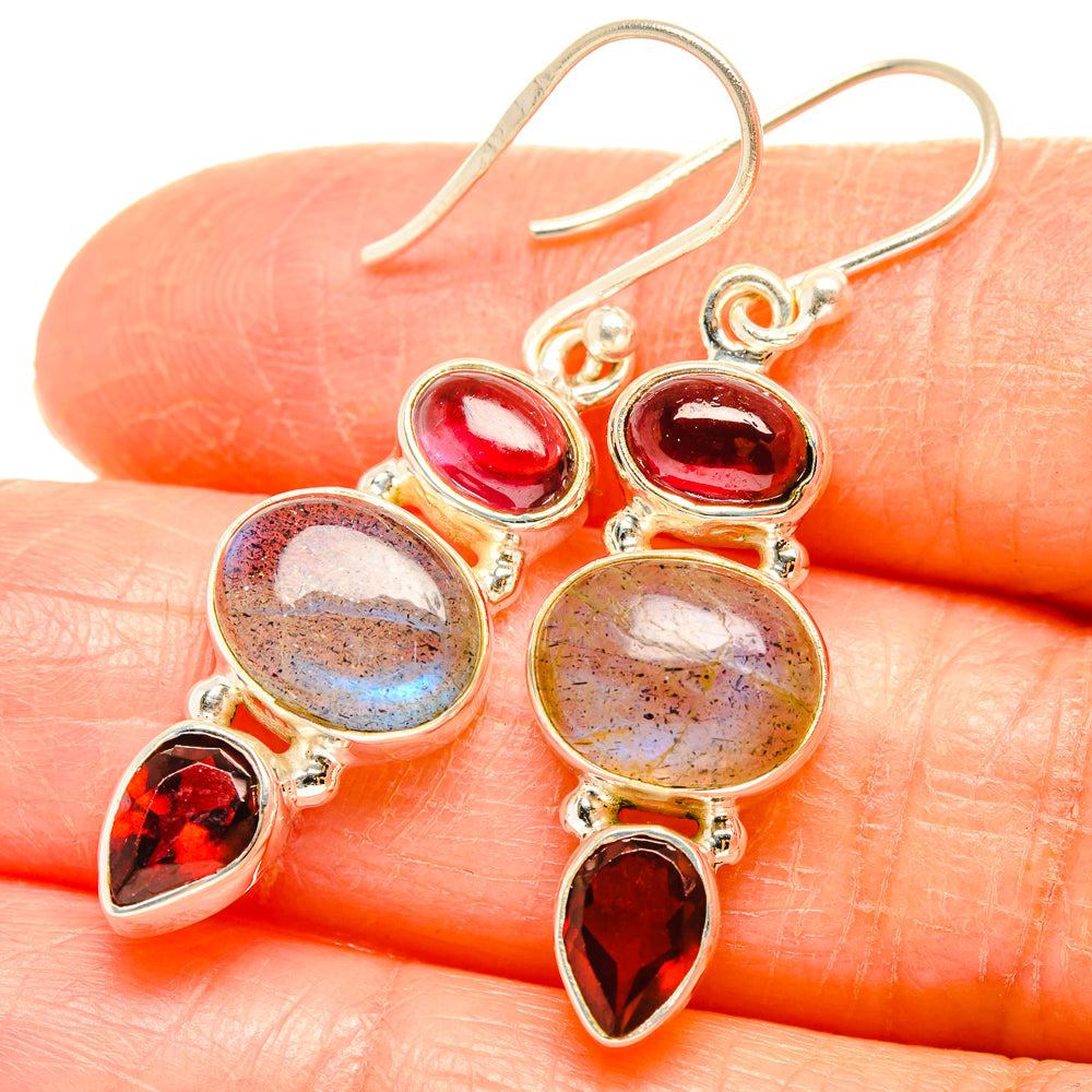 Close-up of drop earrings with pink oval stones, round labradorite, and red teardrops