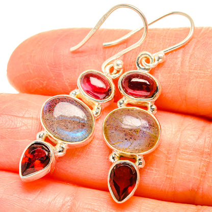 Close-up of drop earrings with pink oval stones, round labradorite, and red teardrops