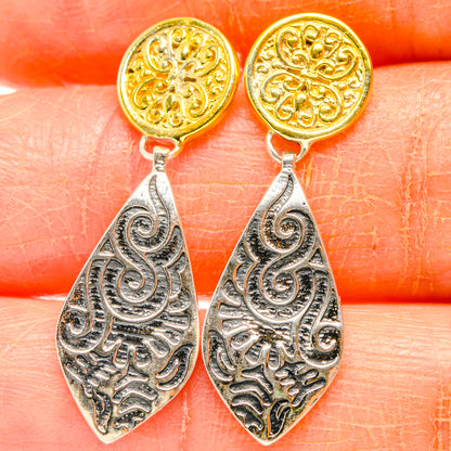 Close-up engraved drop earrings: gold round studs above silver filigree teardrops