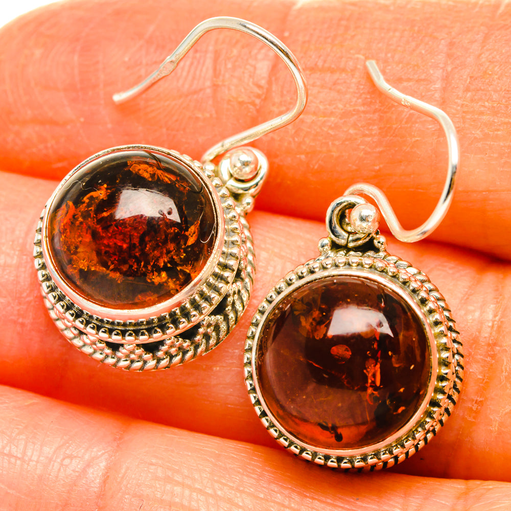 Close-up of round amber earrings with silver rope border and fishhook backs