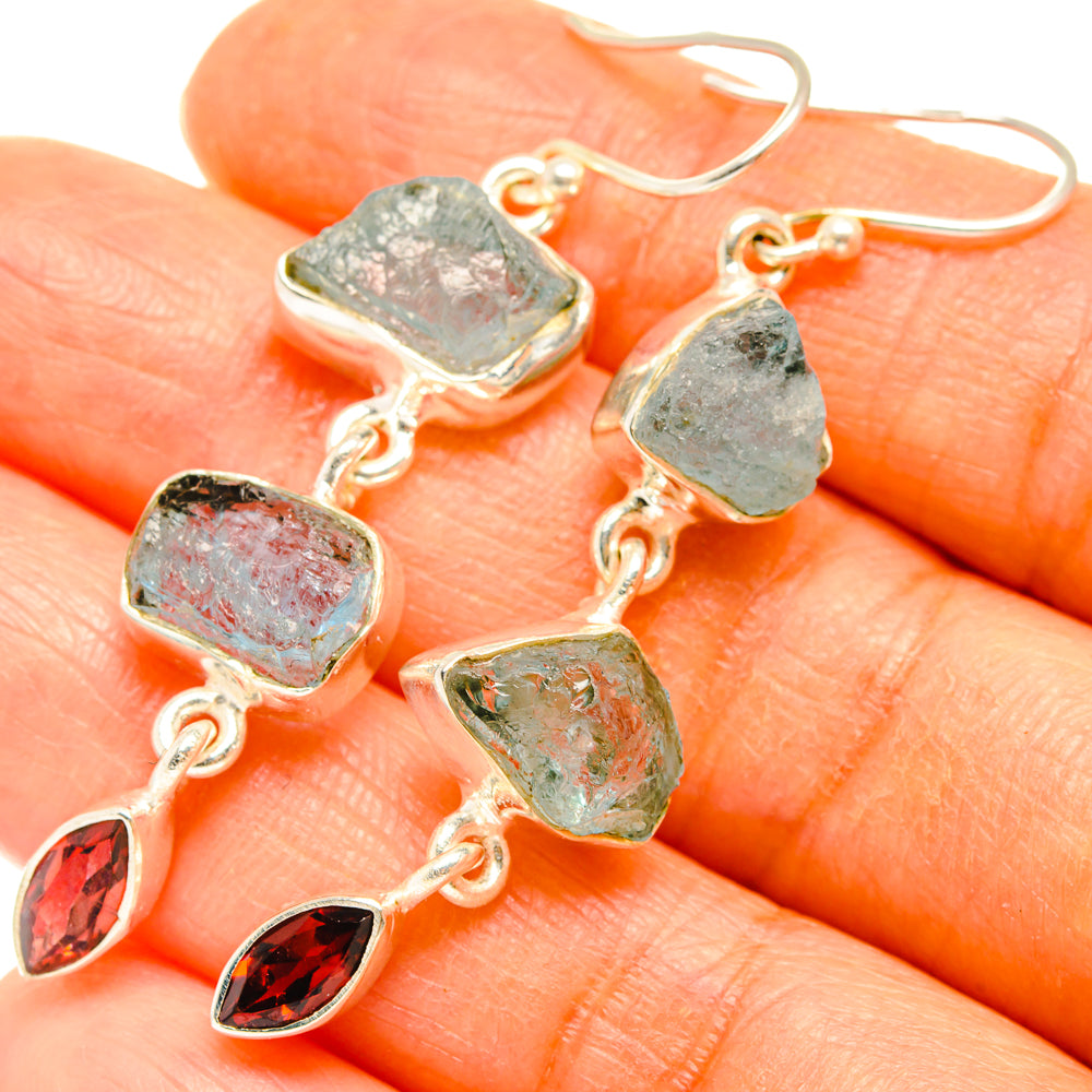 Silver-tone dangling earrings with rough aqua-blue stones and red garnet drops, close-up