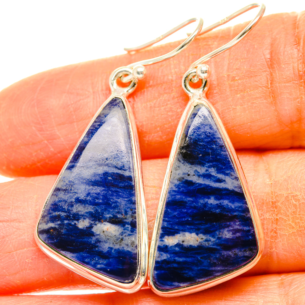 Sterling silver sodalite drop earrings with blue teardrop stone on finger