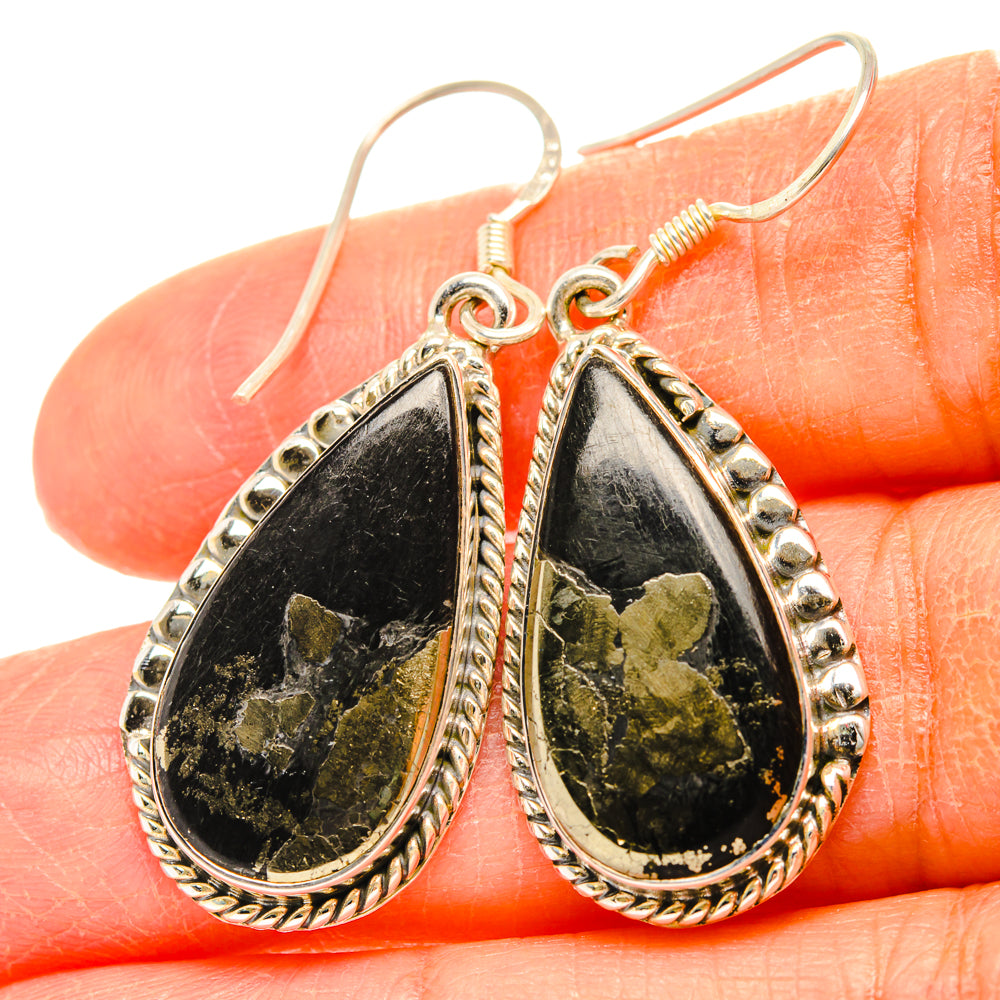 Close-up gold-tone teardrop earrings with black and gold flecked stone, hook drops