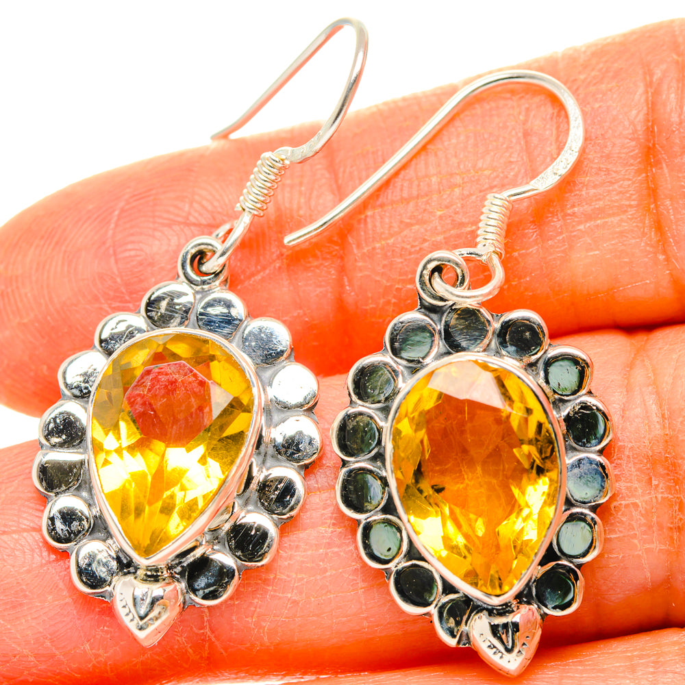 Close-up teardrop citrine dangle earrings, faceted yellow stones in silver scalloped setting