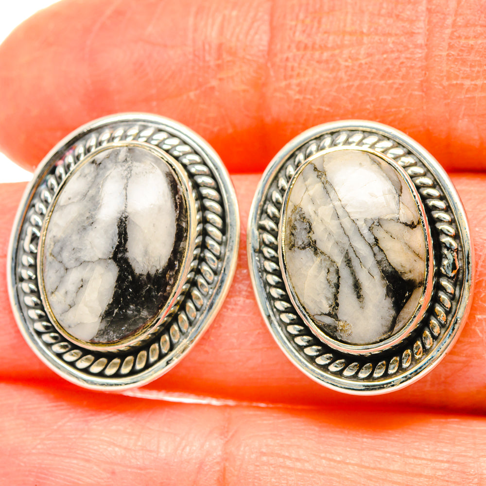 Close-up of oval pinolith jasper stud earrings, white stone with dark veins, silver bezel.