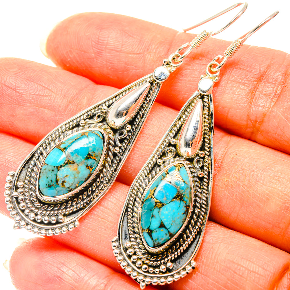 Turquoise teardrop earrings with ornate silver-tone settings and hook backs