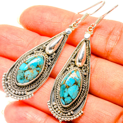Turquoise teardrop earrings with ornate silver-tone settings and hook backs