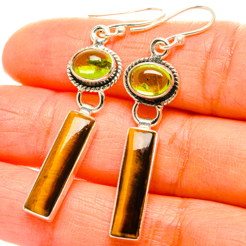 Close-up of sterling silver earrings with green cabochon and amber tiger-eye rectangular drops