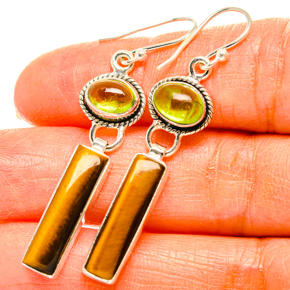 Peridot and tiger eye drop earrings close-up: round green stones with tiger-eye bars